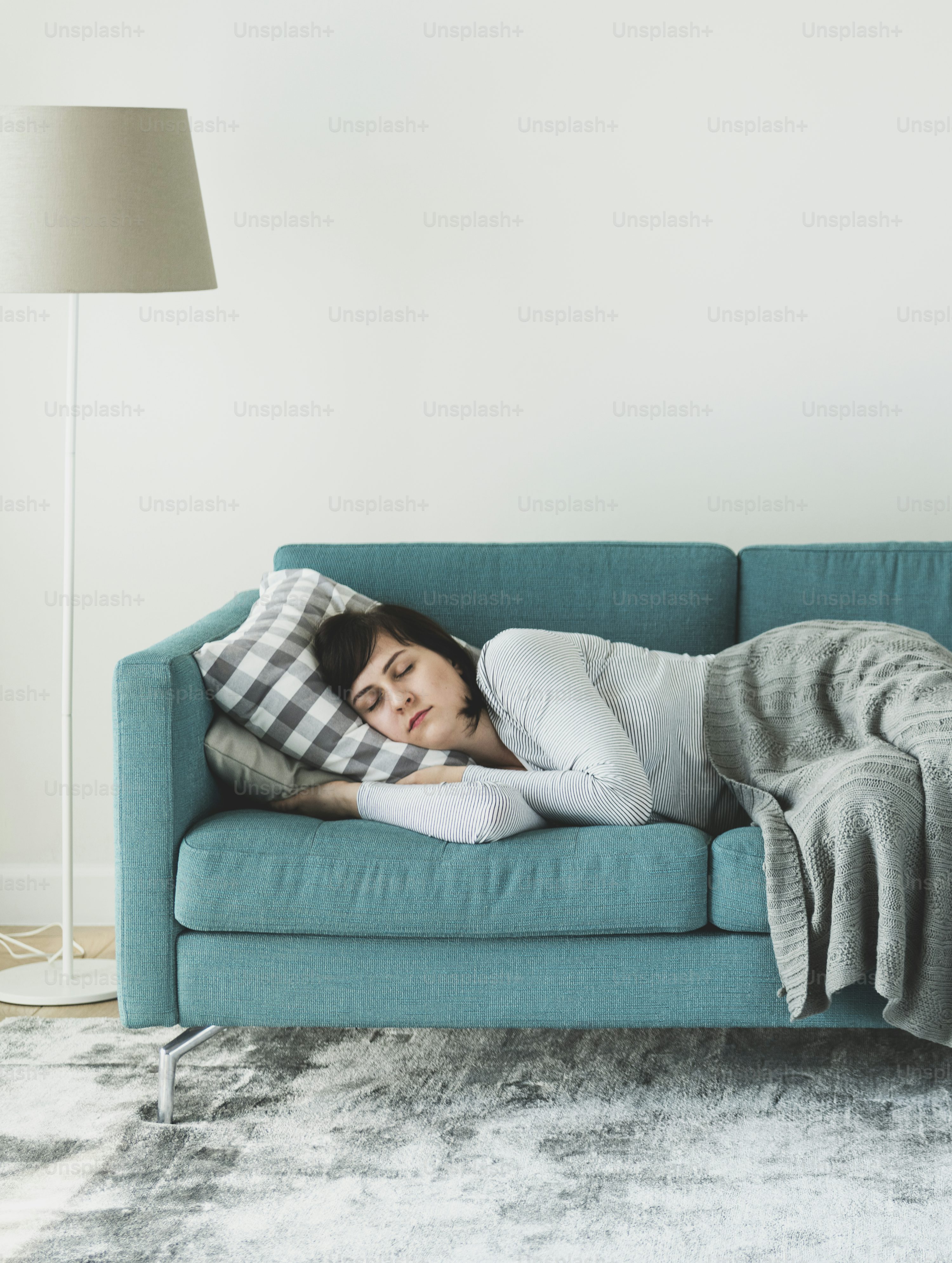 A woman sleeping on a light-colored sofa during the day