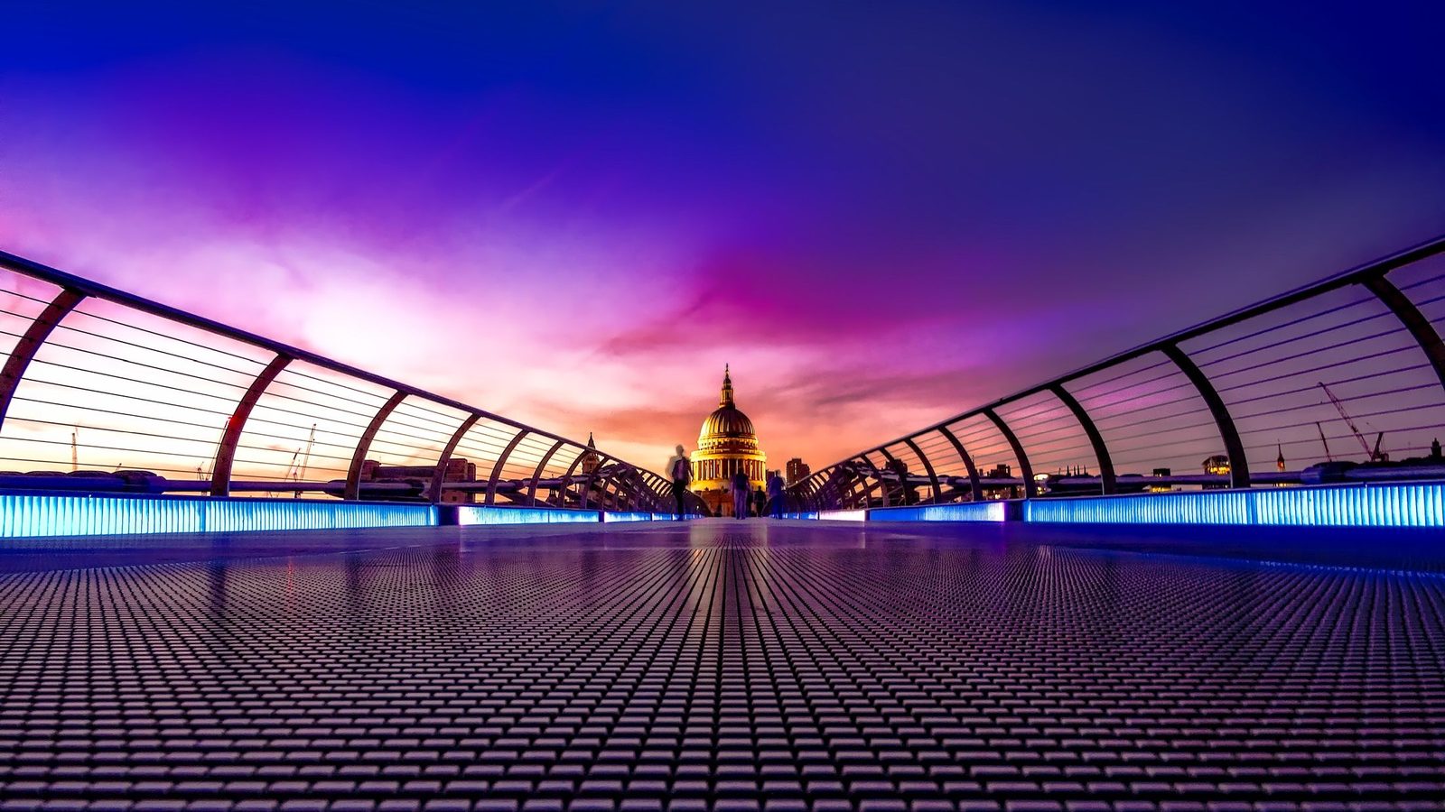 Dawn light in purple and pink tones breaks over a futuristic covered walkway with a domed cathedral visible in the distance, suggesting the start of a new day