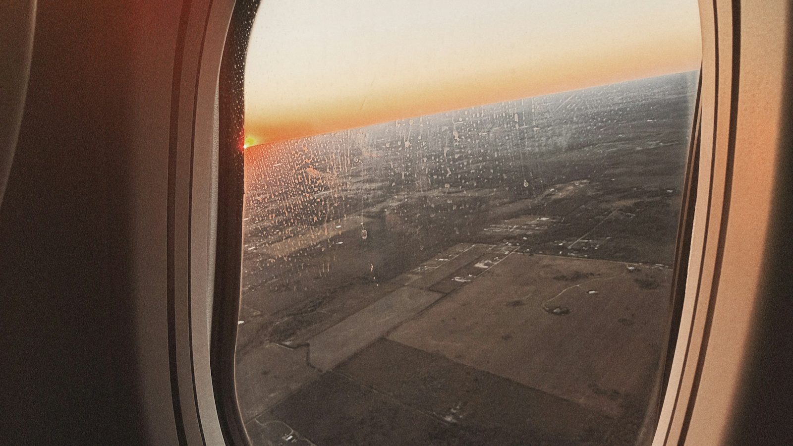 Sunrise seen through a rain streaked airplane window during a flight