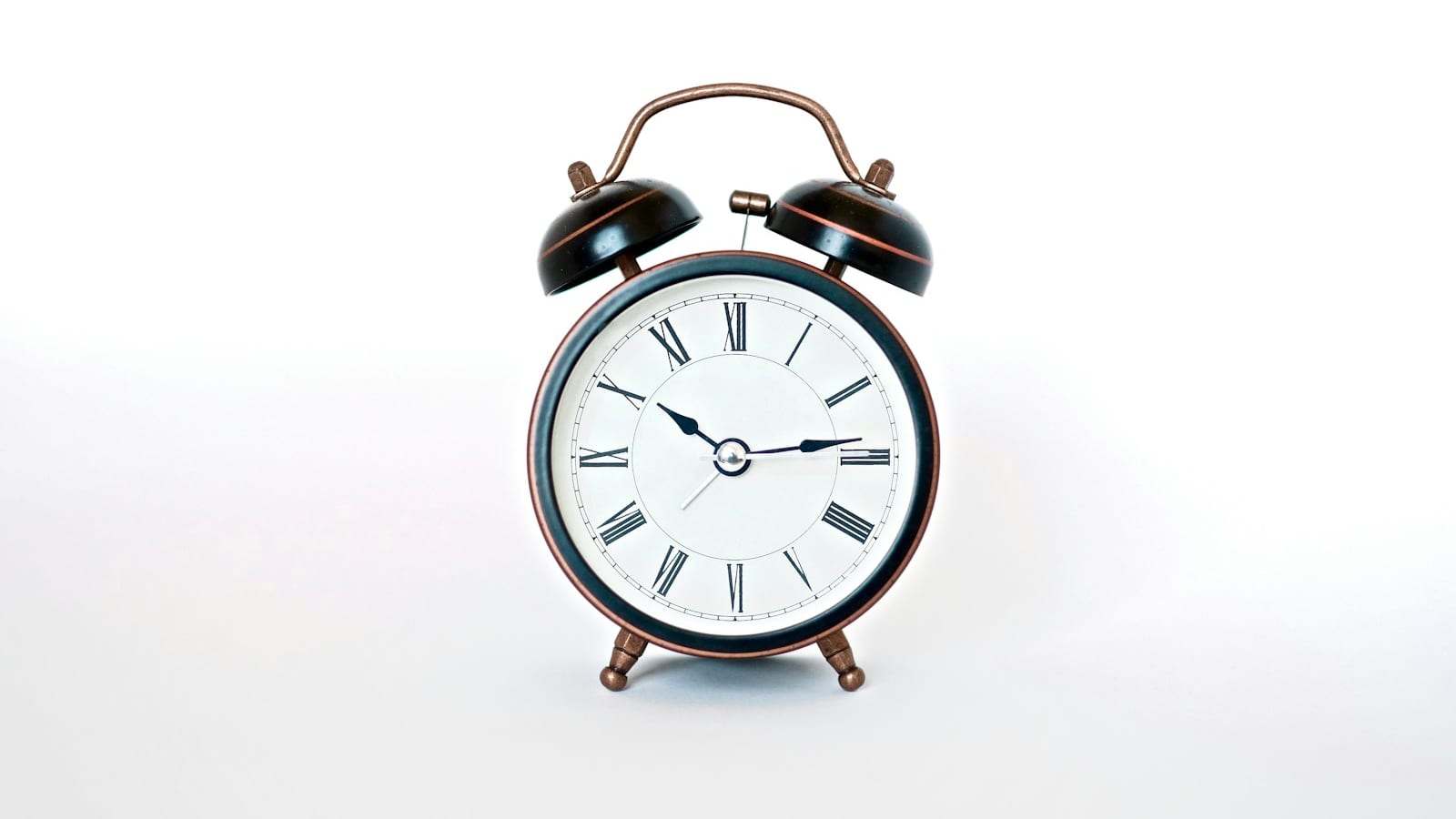 A black and copper twin-bell alarm clock against a plain white background